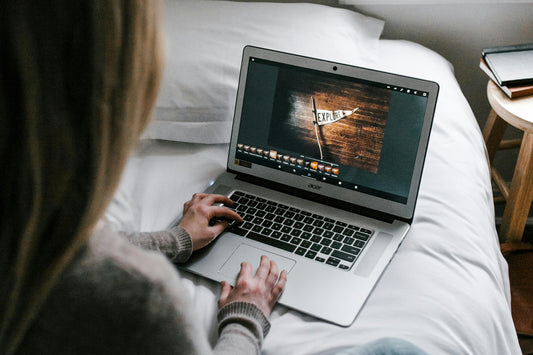 woman on laptop sitting on her bed